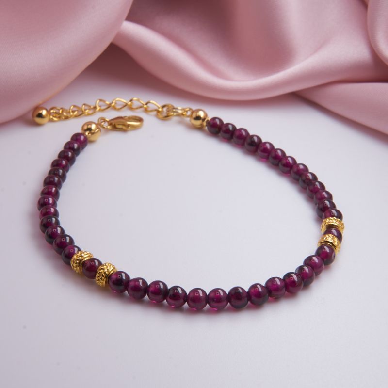 Nahaufnahme eines roten Granat-Armbandes, liegend auf neutralem Untergrund.